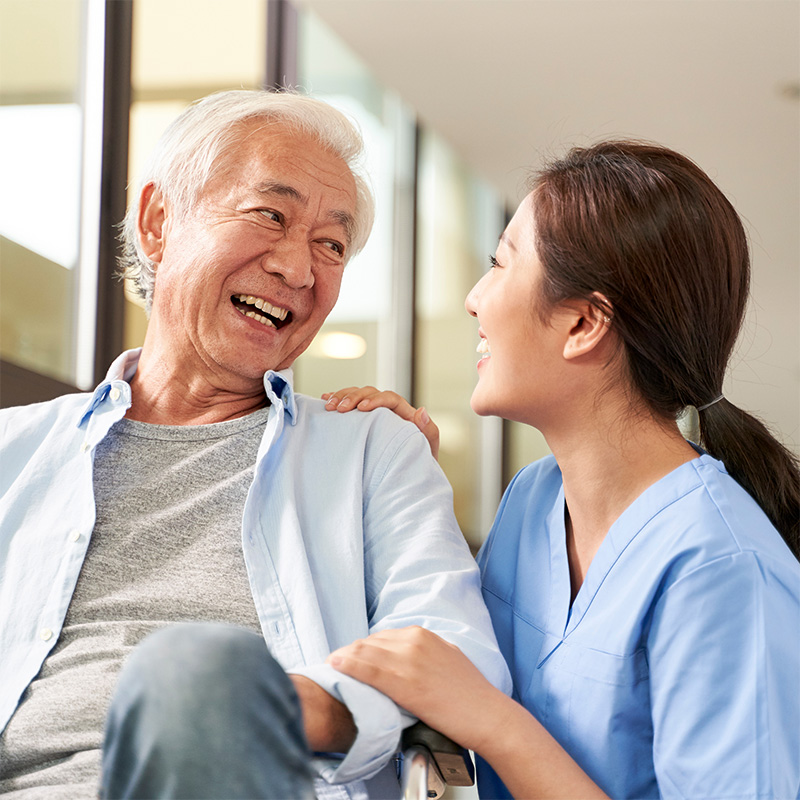 yolo-800x800-84 Nurse leaning down to speak with a resident seated on a chair